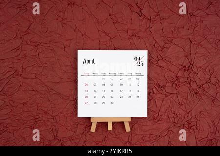 Calendrier d'avril 2025 sur fond de papier froissé rouge. Directement au-dessus. Pose à plat. Banque D'Images