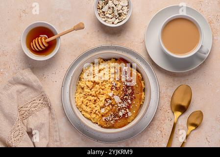 Photographie alimentaire de bouillie de millet avec banane caramélisée, noix de pécan, noix, flocons de noix de coco, chia, graines de lin, miel, thé au lait d'amande Banque D'Images