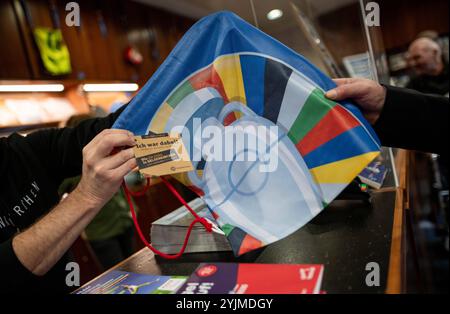 Gelsenkirchen, Allemagne. 15 novembre 2024. Un sac fabriqué à partir des matériaux du Championnat d'Europe est remis sur le comptoir. Les produits fabriqués à partir de bannières, de bavoirs et de drapeaux du Championnat d'Europe sont maintenant vendus quatre mois après le Championnat d'Europe de football. Le projet est présenté par la ville et les partenaires de coopération. Les profits iront à une bonne cause. Crédit : Fabian Strauch/dpa/Alamy Live News Banque D'Images