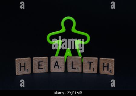 Gros plan de l'homme en plastique vert fluorescent avec des lettres « SANTÉ » sur la surface noire Banque D'Images