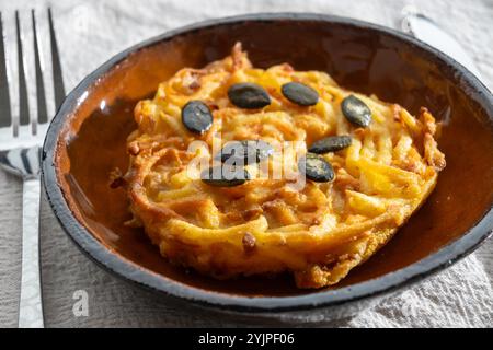 Galettes grillées de citrouille, rosti ou latkes, confectionnées à la fron de courge et de pomme de terre décorées de graines de citrouille en gros plan Banque D'Images