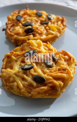 Galettes grillées de citrouille, rosti ou latkes, confectionnées à la fron de courge et de pomme de terre décorées de graines de citrouille en gros plan Banque D'Images