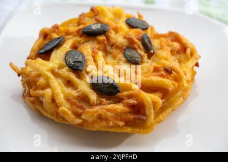 Galettes grillées de citrouille, rosti ou latkes, confectionnées à la fron de courge et de pomme de terre décorées de graines de citrouille en gros plan Banque D'Images