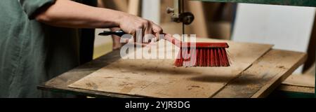 carpenter nettoie méticuleusement les surfaces en bois dans son atelier vibrant rempli d'outils et de matériaux. Banque D'Images