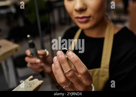 Un artisan qualifié tient soigneusement un bijou précieux tout en travaillant sur son métier. Banque D'Images
