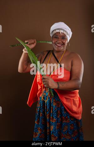 Salvador, Bahia, Brésil - 21 octobre 2024 : femme en vêtements traditionnels Candomblé, tenant l'épée de la plante Saint George, posant pour une photo. Salv Banque D'Images