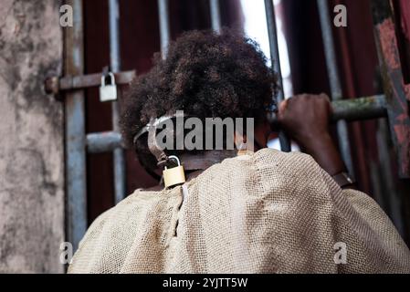 Portrait d'une femme noire habillée en esclave, enchaînée avec un masque de fer sur sa bouche, face à la clôture de fer. L'esclavage au Brésil. Representati Banque D'Images