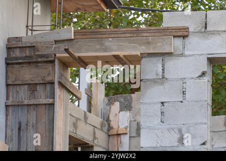 Un gros plan de la construction de poutres en bois sur le dessus d'un mur de blocs de cendre, en cours de construction dans la cour avant. Banque D'Images
