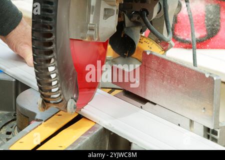 Scie à onglets manuelle, coupant soigneusement le morceau de bois dans des tours de lame de scie d'atelier bien éclairés, mettant en évidence l'accent sur la précision du travail du bois. Banque D'Images