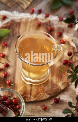 Une tasse de thé à la hanche rose sur une table avec des baies fraîches Banque D'Images
