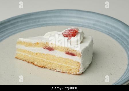 Un petit shortcake japonais à la fraise sur une grande assiette élégante sur une table blanche. Banque D'Images