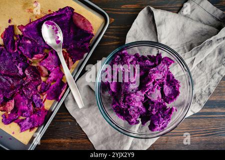 Patates douces pelées et coupées dans un bol en verre : trois patates douces violettes rôties coupées de leur peau dans un petit bol Banque D'Images