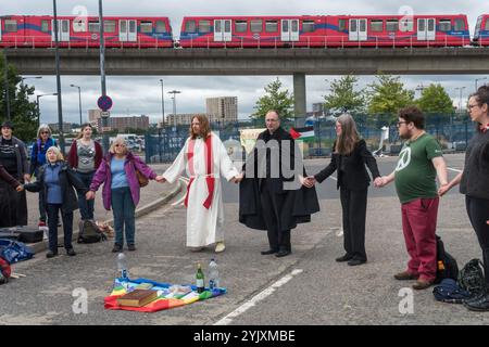 London, UK. 5th September 2017. People hold hands at the end of a mass on the road leading into the world's largest arms fair held in London's docklands. The series of events on the 'No Faith in War' day of the protests was organised by various faith groups. Before I arrived there had been a lock-in on the approach road stopping deliveries coming to set up the fair through the East gate. This was followed by a Quaker meeting at the side of the road during which a number of people stood or sat to block the road and several who refused to move were arrested. Then four protesters descended on rop Stock Photo