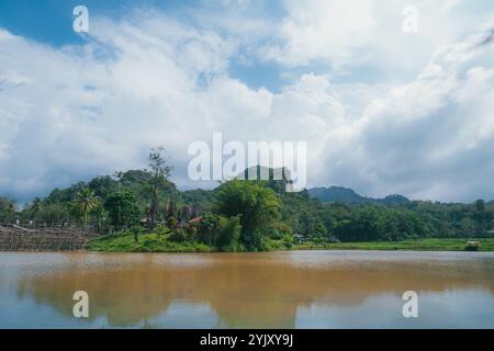 Un étang avec de grands murs de pierre dans la région de Kete Kesu à ​​Tana Toraja. Le ciel semble lumineux et nuageux Banque D'Images