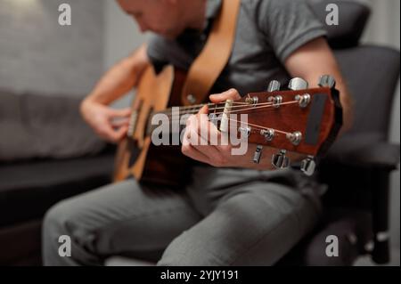 Guitariste payant une guitare acoustique au bureau. Portrait musicien masculin jouant un instrument de musique Banque D'Images