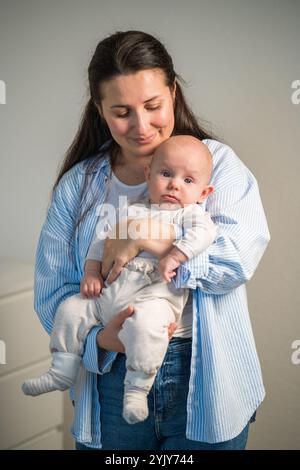 Une maman tient doucement un bébé mignon dans ses bras à l'âge de quelques mois. Amour d'une maman, maternité, enfance Banque D'Images