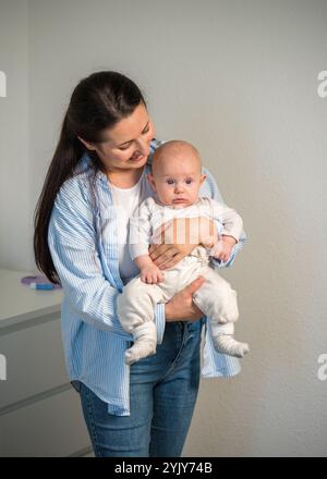 Une maman tient doucement un bébé mignon dans ses bras à l'âge de quelques mois. Amour d'une maman, maternité, enfance Banque D'Images