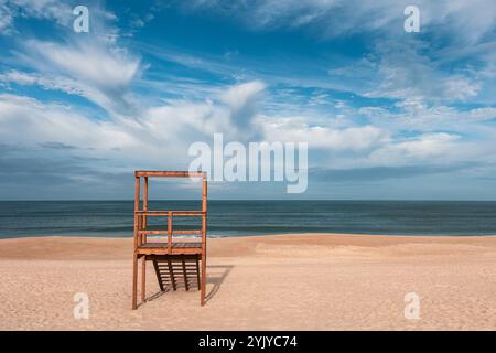 Une tour de sauveteur en bois se dresse solitaire sur une vaste plage de sable, surplombant l'océan Atlantique bleu calme sous un ciel partiellement nuageux Banque D'Images