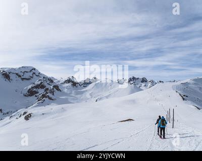 Deux randonneurs explorent le paysage enneigé de serre Chevalier près de Briançon. Le paysage alpin pittoresque et le ciel dégagé offrent une magnifique toile de fond hivernale Banque D'Images