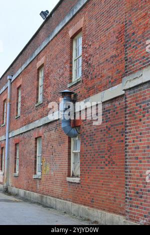 Royal Clarence Yard, Weevil Lane, Gosport, Hampshire, Angleterre. 11 novembre 2024. La zone est progressivement rénovée avec un mélange d'entreprises et de logements privés et sociaux. Cette photo montre une cheminée ou un échappement à l'extérieur de l'ancien magasin de rhum construit en briques. Banque D'Images