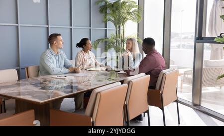 Équipe d'affaires multiethnique de jeunes collègues parlant à la table de réunion Banque D'Images