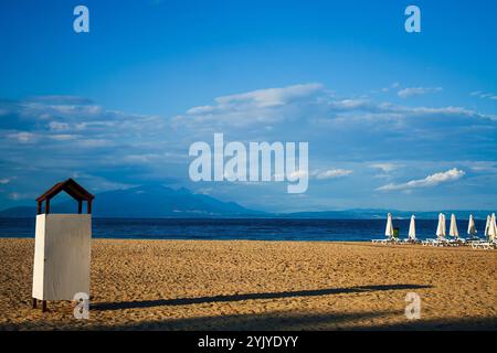 Une cabane changeante sur une plage. Représentant une cabine de changement solitaire sur une plage, avec chaises longues et parasols dans le dos Banque D'Images