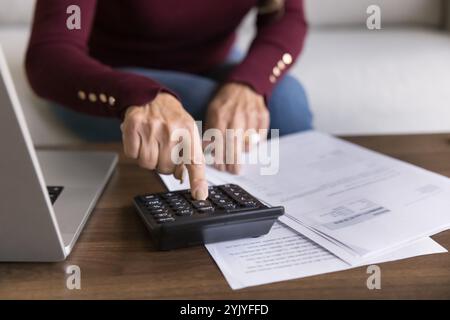 Mains de la femme retraitée senior à l'aide de la calculatrice à la maison Banque D'Images
