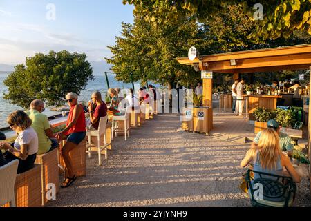 Sirmione, Italie - Sep 21st, 2024 : les gens profitent d'un coucher de soleil détendu dans un bar au bord du lac surplombant le lac de Garde Banque D'Images