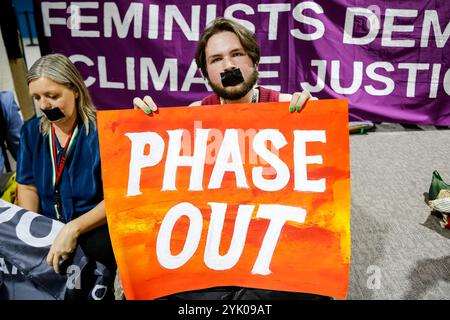 Bakou, Azerbaïdjan, le 16 novembre 2024. Un jeune adulte tient une bannière « retrait progressif » alors que des centaines de militants climatiques protestent pour influencer les décisions sur le financement du Sud mondial devant les salles plénières de la zone bleue lors de la COP29 de la Conférence des Nations Unies sur les changements climatiques, un événement organisé par la CCNUCC au stade olympique de Bakou. La COP29, qui se déroule du 11 au 22 novembre, se concentre sur le financement climatique. Ce fut la plus grande protestation de la COP29, appelée la Journée d’action. Cette année, la Journée d’action était petite, comparée aux précédentes COP. À Bakou, les militants n'ont pas reçu l'autorisation de chanter ou de marcher dans les couloirs de la VE Banque D'Images