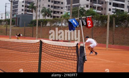 Tableau de bord sur un court de tennis en terre battue avec deux joueurs en arrière-plan. Banque D'Images