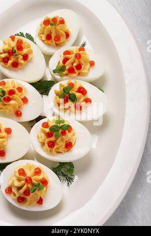 Oeufs farcis, avec caviar rouge, micro verdure, snack, sur une assiette blanche, vue de dessus, gros plan, pas de gens Banque D'Images