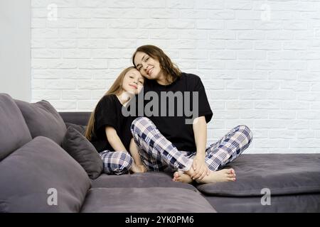 Heureux portrait de famille de la mère et de la fille assis sur le canapé et incliné la tête l'un à l'autre Banque D'Images