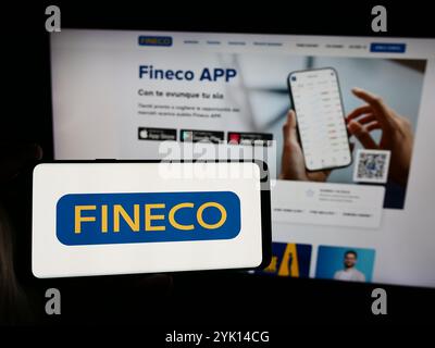 Dans cette illustration photo, une personne tient un smartphone avec le logo de la société italienne de services financiers FinecoBank S.p.A. en face du site Web. Banque D'Images