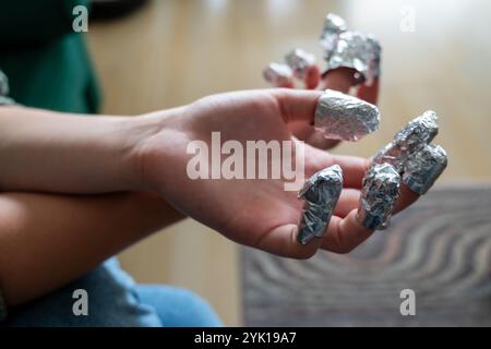 un photogrtaph montrant comment enlever le vernis à ongles en gel en appliquant de l'acétone et en enveloppant les doigts dans une feuille d'étain ou d'aluminium Banque D'Images