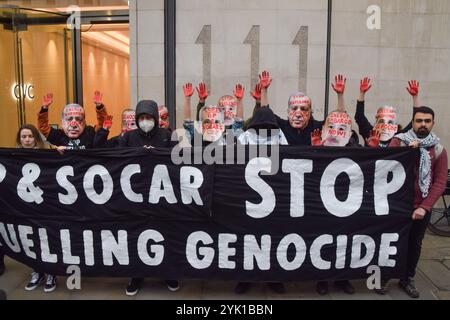 Londres, Royaume-Uni. 16 novembre 2024. Des manifestants portant des masques du président turc Recep Erdogan et d'autres se tiennent les mains couvertes de faux sang à côté d'une banderole exigeant la fin du génocide devant les bureaux de la société SOCAR on the Strand pendant la manifestation. Les manifestants ont défilé dans le centre de Londres pour exiger la justice climatique et la fin des combustibles fossiles, et en solidarité avec la Palestine, alors que la COP29 se poursuit en Azerbaïdjan. Crédit : SOPA images Limited/Alamy Live News Banque D'Images