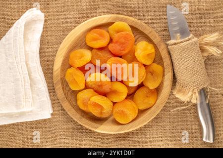 Abricots secs sucrés avec des plats faits maison sur toile de jute, macro, vue de dessus. Banque D'Images