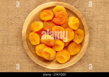 Abricots secs sucrés avec des plats faits maison sur toile de jute, macro, vue de dessus. Banque D'Images