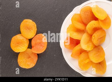 Abricots secs sucrés avec des plats faits maison sur pierre d'ardoise, macro, vue de dessus. Banque D'Images