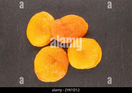 Abricots secs sucrés avec des plats faits maison sur pierre d'ardoise, macro, vue de dessus. Banque D'Images