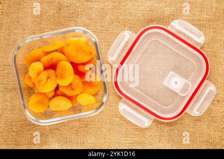 Abricots secs sucrés avec des plats faits maison sur toile de jute, macro, vue de dessus. Banque D'Images