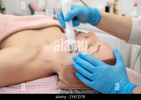 Fermez les mains du médecin dans des gants de protection en utilisant le composant de main de la machine à peeling visage hydra avec rouleau. entretien de propreté Banque D'Images