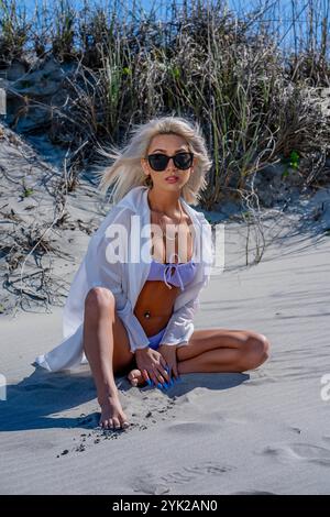 Une femme magnifique se détend sur la plage dans un bikini qui met en valeur ses courbes. Elle apprécie l'eau fraîche et se prélasse sous le soleil chaud, trempant dans son R Banque D'Images