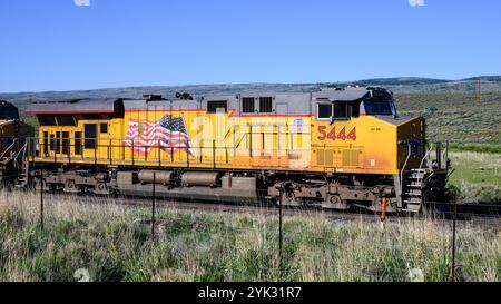 Helper, UT, États-Unis - 11 juin 2024 ; locomotive de train Union Pacific Feight dans l'Utah rural avec logo du drapeau américain Banque D'Images