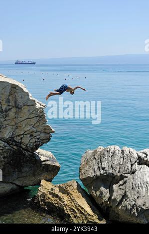 Adolescents plongant depuis des rochers à l'extérieur de la plage de Jezinac au pied de la colline de Marjane, Split, Croatie, Europe du Sud-est Banque D'Images