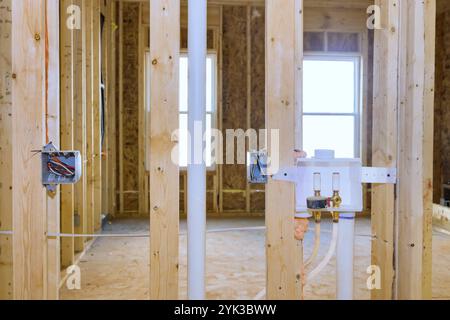 Construction d'un nouvel intérieur de maison avec cadre en bois apparent, plomberie reliant les systèmes de buanderie, câblage électrique pendant la rénovation Banque D'Images