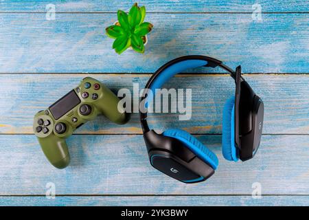 10 OCTOBRE 2024 New York NY US : casque bleu repose à côté de la manette de jeu verte sur une table en bois vieilli Banque D'Images