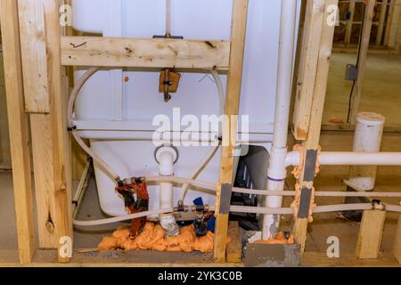 Les travailleurs installent la plomberie reliant les systèmes de bain à l'intérieur de la zone de bâtiment résidentiel caractéristiques exposées charpente, tuyaux, matériaux d'isolation Banque D'Images