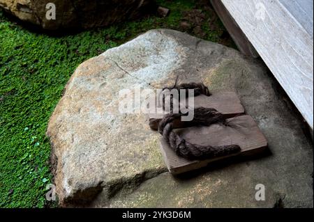 Paire de geta traditionnelles (sandales en bois) assis sur une marche rocheuse à l'entrée d'une résidence dans le village Fukiya Furusato à Okayama, au Japon. Banque D'Images