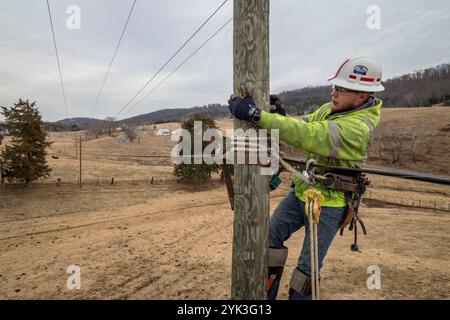 Brandon Joueur de contrat Sims a grimpé poteau au châssis pour les tenir sur le fil comme Virginia's BARC Electric Cooperative ouvre la voie dans la région de Lexington en Virginie, l'installation de câbles à fibres optiques le réseau électrique existant, ce qui permettra de porter à haute vitesse à large bande fiable pour le secteur pour la première fois. Les zones rurales où les entreprises et les consommateurs résidentiels utiliser le service à large bande sont plus susceptibles de profiter de l'augmentation des revenus, le taux de chômage plus faible et une plus forte croissance que celles qui n'ont pas le haut débit. Parce qu'à large bande offre la connectivité aux zones rurales, l'éducation, soins de santé et d'autres servic Banque D'Images