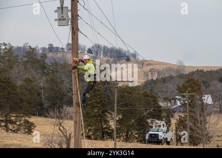 Brandon Joueur de contrat Sims a grimpé poteau au châssis pour les tenir sur le fil comme Virginia's BARC Electric Cooperative ouvre la voie dans la région de Lexington en Virginie, l'installation de câbles à fibres optiques le réseau électrique existant, ce qui permettra de porter à haute vitesse à large bande fiable pour le secteur pour la première fois. Les zones rurales où les entreprises et les consommateurs résidentiels utiliser le service à large bande sont plus susceptibles de profiter de l'augmentation des revenus, le taux de chômage plus faible et une plus forte croissance que celles qui n'ont pas le haut débit. Parce qu'à large bande offre la connectivité aux zones rurales, l'éducation, soins de santé et d'autres servic Banque D'Images